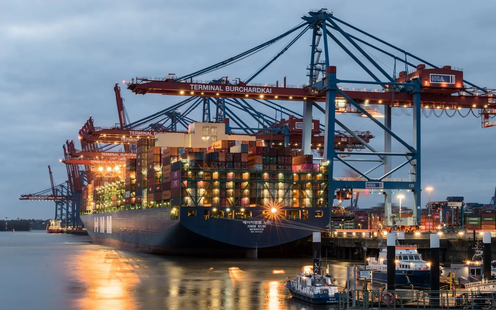 Tàu container cập cảng, cần cẩu bốc dỡ hàng lúc hoàng hôn